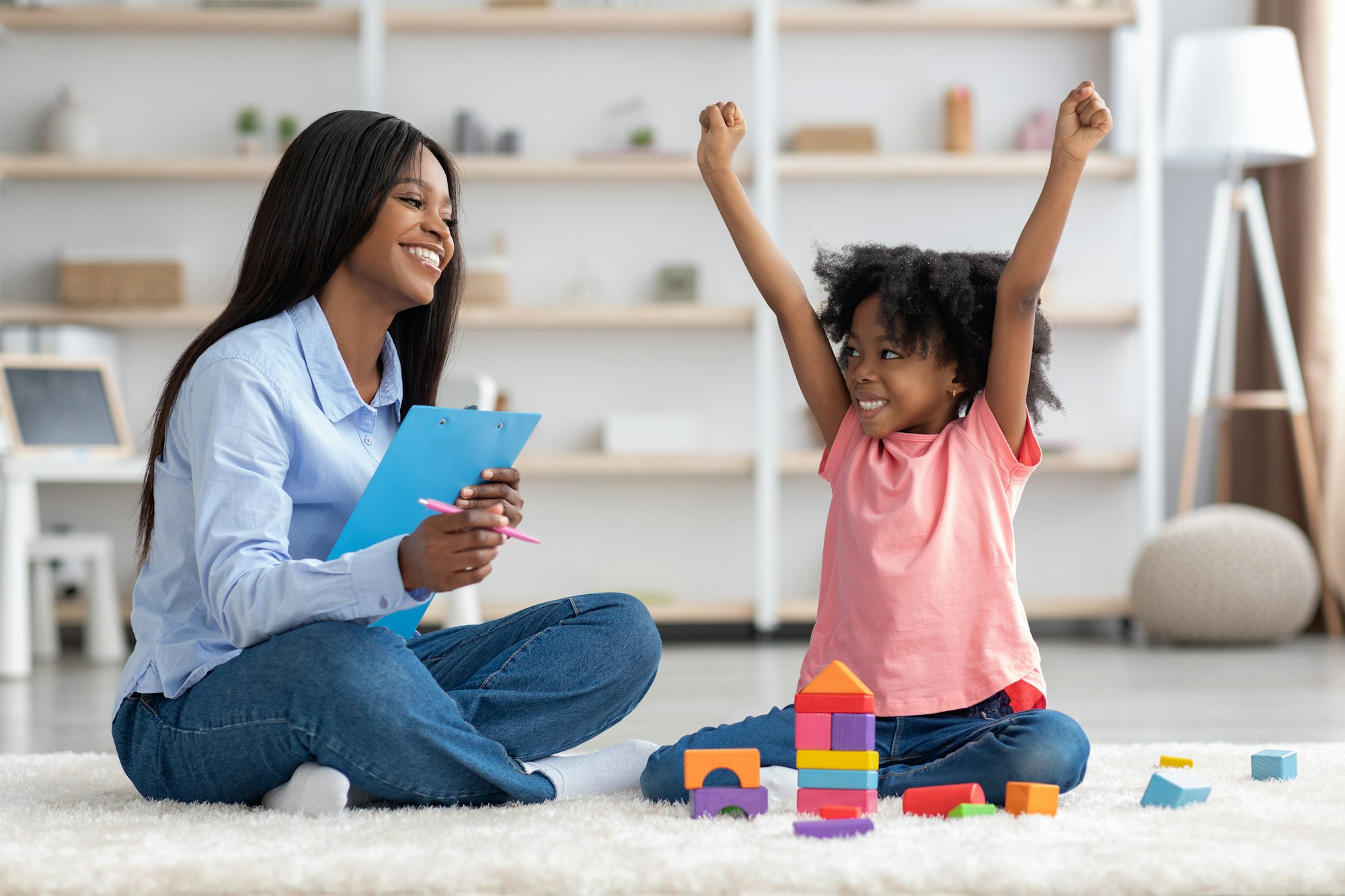 Emotional little girl raising hands up, having session with psychologist
